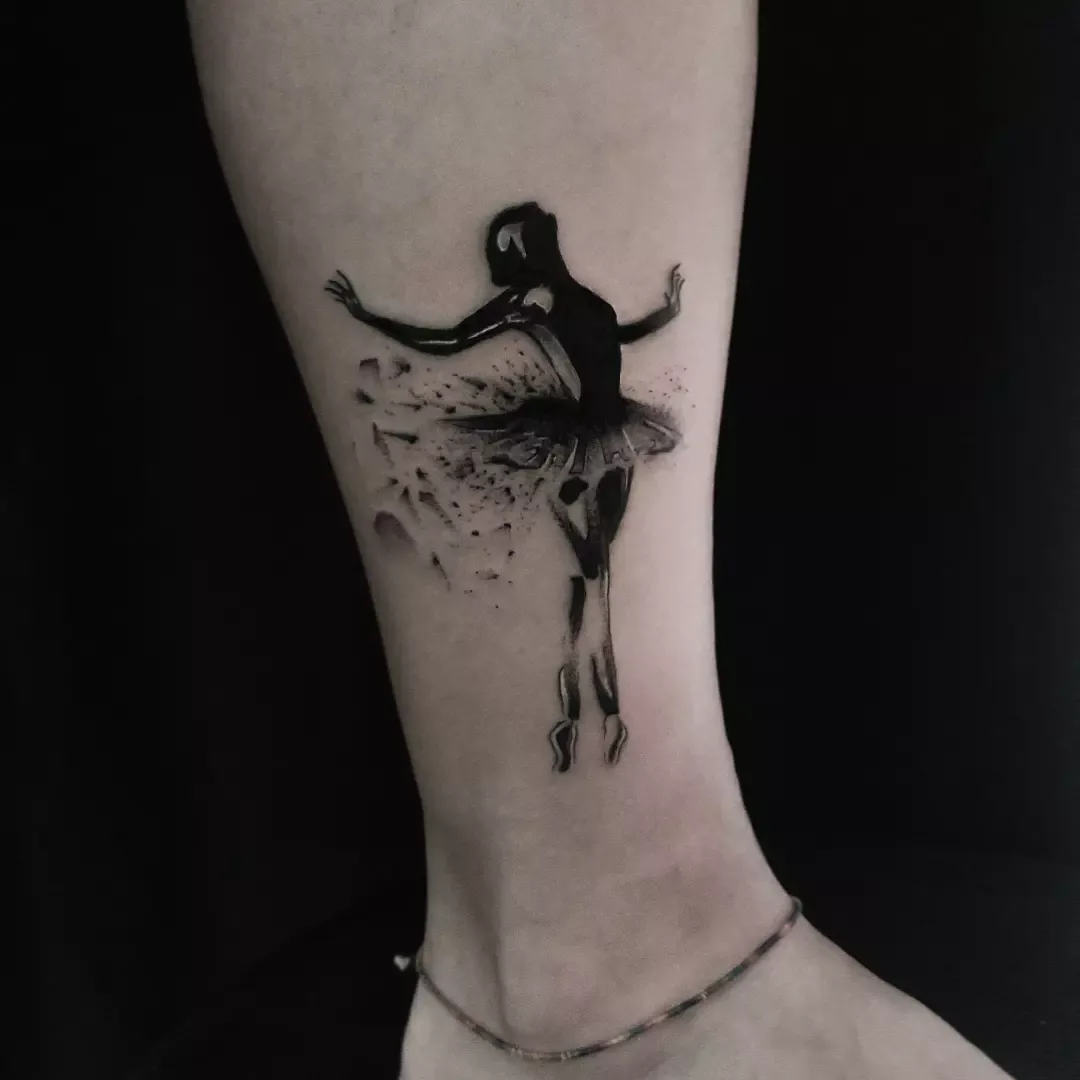 Blackwork ankle tattoo of a ballerina whose skirt dissolves into a scatter of fragments